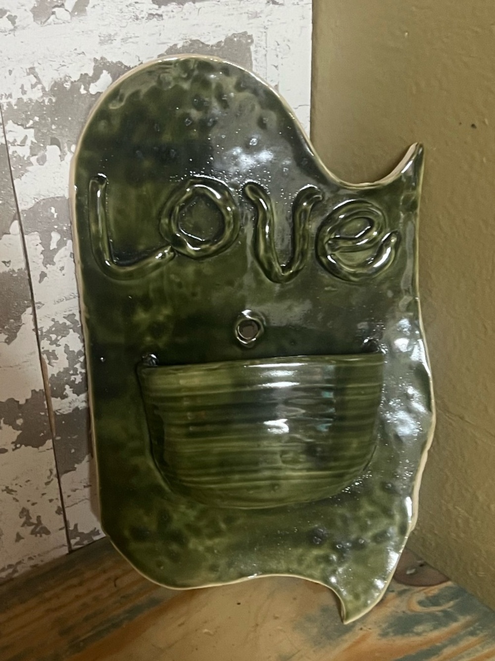Handmade green ceramic wall pocket planter with the word "love" embossed